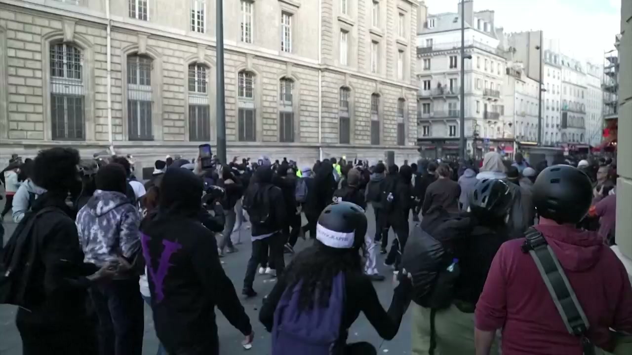 A dense street crowd, including masked people and people wearing helmets, in AFP’s French protest footage
