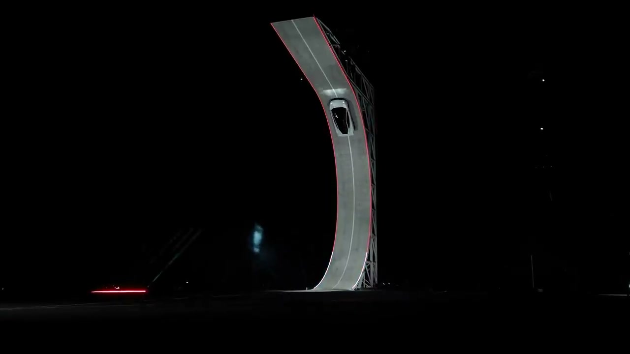 A white Roadster climbing the steep curved ramp during Tesla’s nighttime demonstration